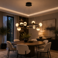 Black and gold chandelier with spherical glass shades hanging above round dining table