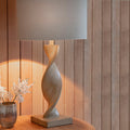 Abia wooden table lamp with twisted base and gray linen shade in warm lighting